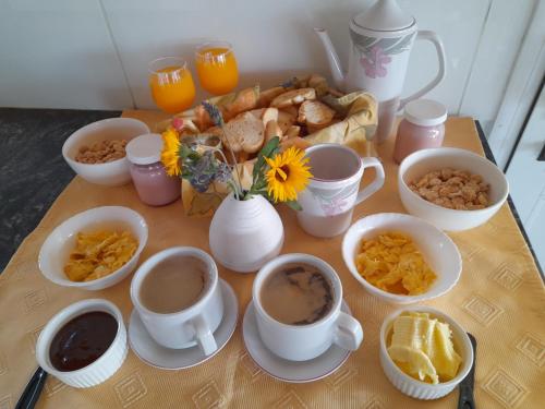 una mesa cubierta con tazas de café y productos para el desayuno en Cabaña Las Retamas en San Andrés de las Sierras
