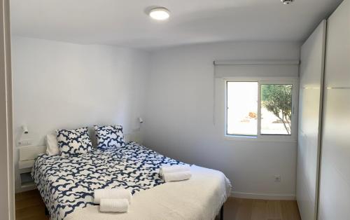 a white bedroom with a bed and a window at Las olas 214 in Maspalomas