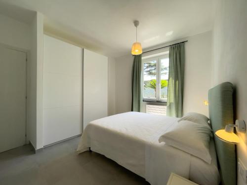 a bedroom with a white bed and a window at Podere Belvedere in Moneglia