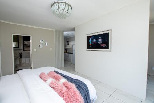 a bedroom with a white bed and a chandelier at Prestigious Apartments in Fourways