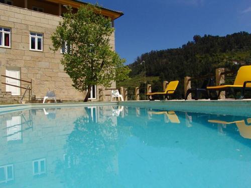 a swimming pool with yellow chairs and a building at Quinta Casal De Vila Pouca in Cinfães