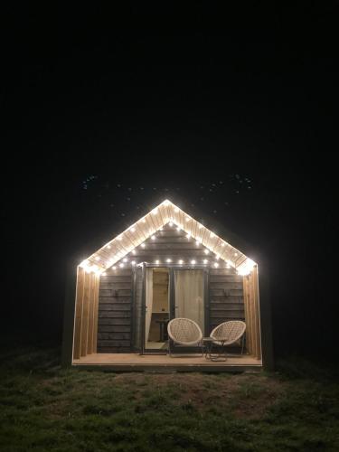 een kleine hut met twee stoelen en verlichting erop bij Craster Coastal Cabins in Craster