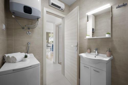 bagno bianco con lavandino e specchio di NNB View a Podstrana
