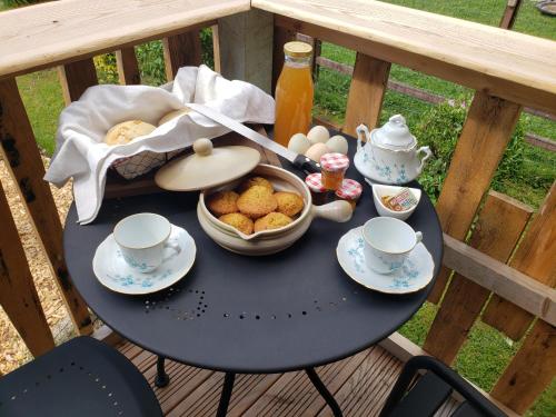 una mesa con comida y tazas y una cesta de huevos en La roulotte tiny house du Mond'idéal, en Leval