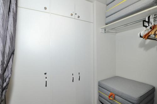 - un placard blanc avec des armoires blanches et un pouf gris dans l'établissement 22#31 Chemin du Hameau - Studio, à Stoneham