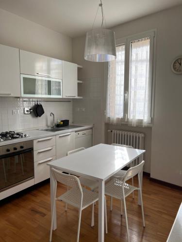 ボローニャにあるCasa Francia Alidosiの白いテーブルと椅子のある白いキッチン