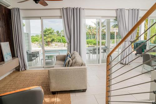 Villas with Private Pool 5 min to Grace Bay beach في Long Bay Hills: غرفة معيشة مع أريكة وشرفة