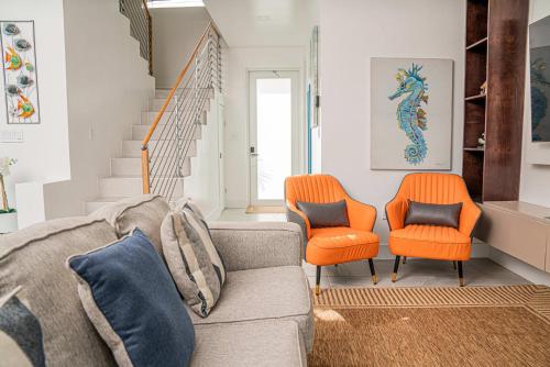 a living room with a couch and two orange chairs at Villas with Private Pool 5 min to Grace Bay beach in Long Bay Hills