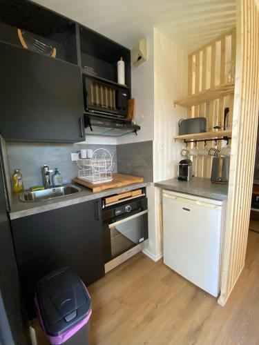 une petite cuisine avec un évier et une cuisinière dans l'établissement Appartement cosy rénové 4 personnes en centre ville Wifi inclus, à Quiberon