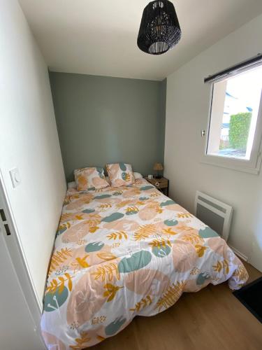une chambre avec un lit avec une couette colorée dans l'établissement Appartement cosy rénové 4 personnes en centre ville Wifi inclus, à Quiberon