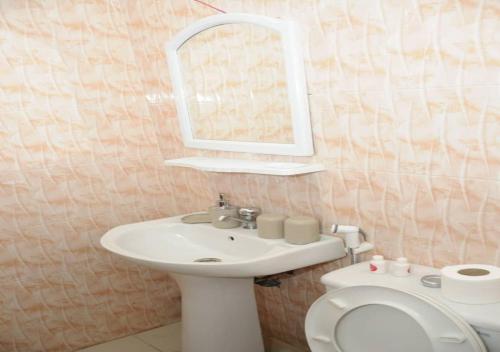 a bathroom with a sink and a toilet and a mirror at Résidence Doux in Dakar