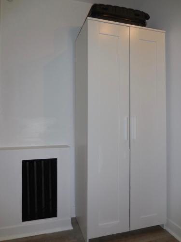 a white cabinet in a room with a fireplace at Joli Studio Parisien in Paris
