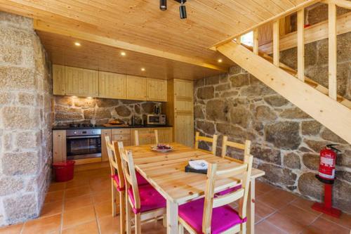 a kitchen with a wooden table and a stone wall at Quinta Casal De Vila Pouca in Cinfães
