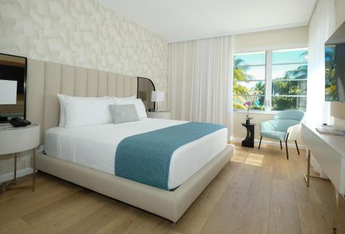 um quarto com uma cama, uma secretária e uma cadeira em Avalon Hotel em Miami Beach