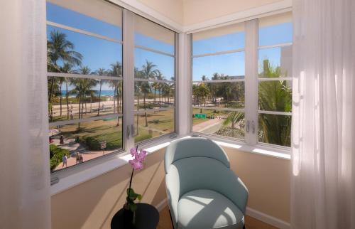 a room with a chair and windows with a view of the beach at Avalon Hotel in Miami Beach
