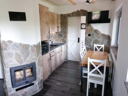a kitchen with a fireplace and a table and a stove at Domek Zielony Widok - noclegi Bieszczady in Lesko
