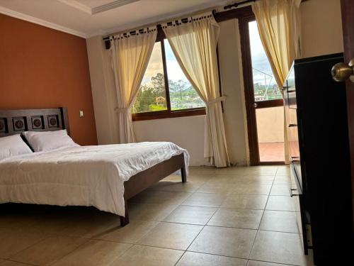 een slaapkamer met een bed en een groot raam bij Casa vacacional in Loja