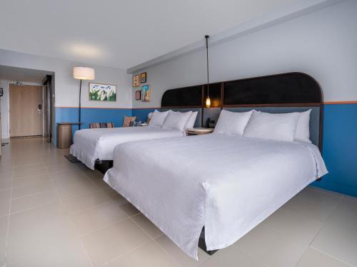 two beds in a hotel room with white sheets at Hilton Garden Inn San Juan Condado in San Juan
