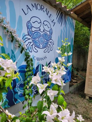 a sign for a garden with white flowers at Cabañas La Moraleja Paraíso Costero in Necoclí