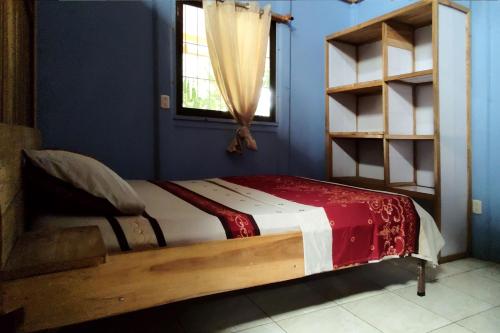 een bed in een blauwe kamer met een raam bij Dominga's Eco-Yellow Hideaway in Puerto Viejo