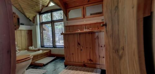 uma casa de banho em madeira com um WC e uma banheira em Bayview Mountain Seafacing Cottages em Hout Bay