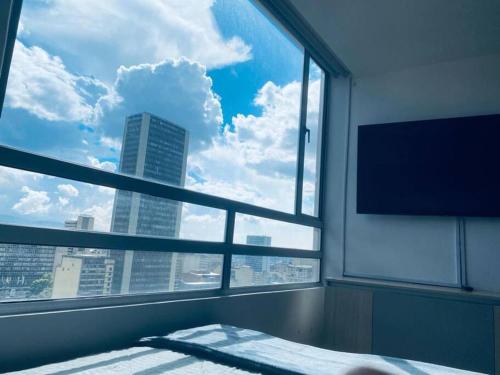 a bedroom with a large window with a view of a city at Torre Acqua - Centro turístico, Vistas Panorámicas in Bogotá