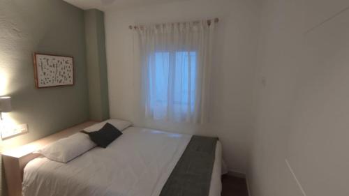 a small bedroom with a bed and a window at Acogedor apt en casco historico in Marbella
