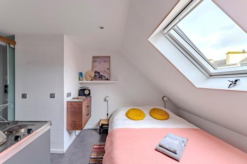ein Schlafzimmer mit einem Bett mit gelben Kissen und einem Fenster in der Unterkunft Charmant studio à deux pas de la gare - Le Nichoir in Rennes