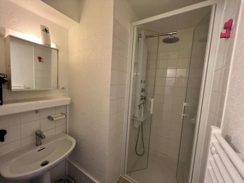 a white bathroom with a shower and a sink at Appartement cosy rénové 4 personnes en centre ville Wifi inclus in Quiberon