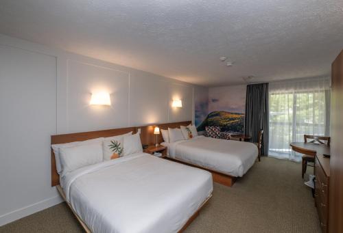 a hotel room with two beds and a desk at Clarion Pointe La Malbaie in La Malbaie