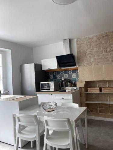 une cuisine avec une table et des chaises dans une cuisine dans l'établissement Gîte de La baleine, à Luc-sur-Mer