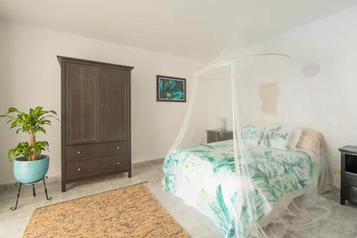 a bedroom with a canopy bed and a potted plant at GeDel Ma Zen Resort in Poris de Abona