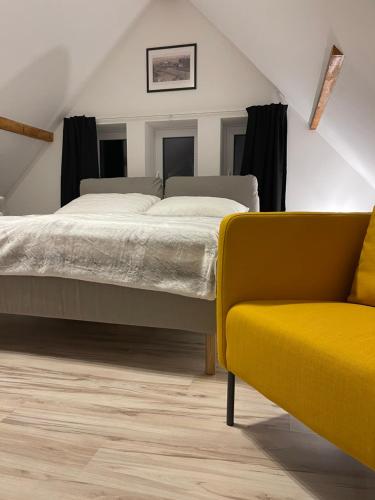 - une chambre avec un lit et une chaise jaune dans l'établissement Apartmánový dům Jánský sen, à Janské Lázně