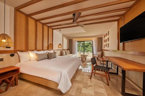 een slaapkamer met een bed, een bureau en een televisie bij Bahia Principe Luxury Akumal - All Inclusive in Akumal