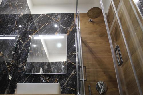 La salle de bains est pourvue d'un lavabo et d'un miroir mural. dans l'établissement BlackWoody Contemporary Rooms - Napoli Centro Storico, à Naples