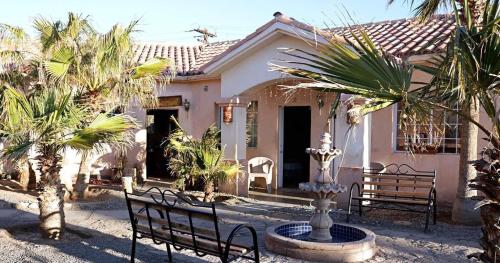 a house with two benches and a fountain in front of it at Costa del Sol Hotel & Sportfishing in Bahía de los Ángeles