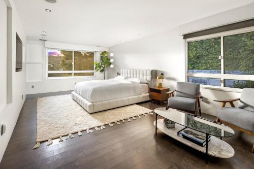 Hollywood Hills Luxury Modern Home with Pool & Sunset views في لوس أنجلوس: غرفة نوم بسرير واريكة وكراسي