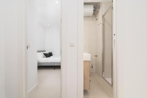 Habitación blanca con cama y espejo en Suite Homes Hesperides 914, en Málaga