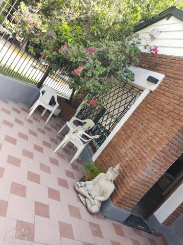 a patio with two white chairs and a statue at Dakini Hostel in Lomas de Zamora