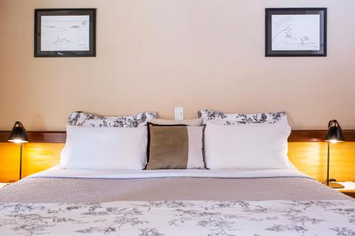 a bedroom with a bed with white sheets and pillows at Pousada Cavaleiro dos Pireneus in Pirenópolis