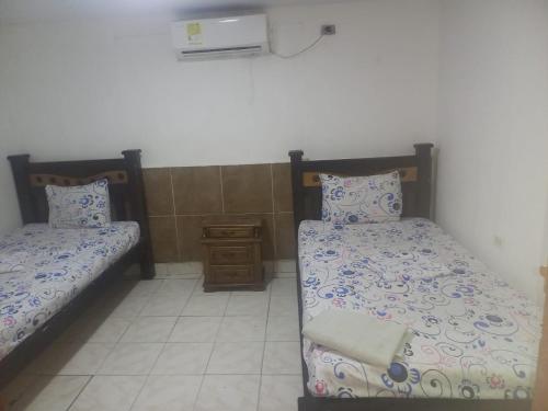 a room with two beds and a night stand at hotel casa del conductor doña silvia in Cartagena de Indias