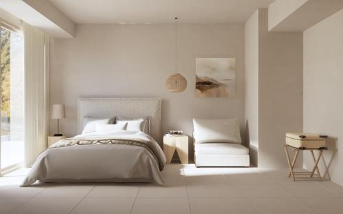 a white bedroom with a bed and a chair at Haus Platanos Apartments & Bungalows by the Sea in Vourvourou