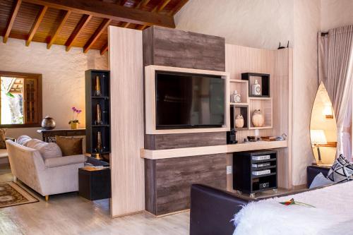 a living room with a tv on a wall at Pousada Cavaleiro dos Pireneus in Pirenópolis