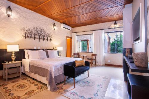 a bedroom with a bed and a chair in a room at Pousada Cavaleiro dos Pireneus in Pirenópolis