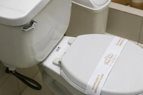 a toilet with a white seat with a sign on it at Plaza Mayor Lima in Lima