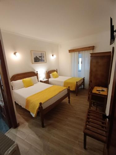 a hotel room with two beds with yellow sheets at Casa 42 in Monção