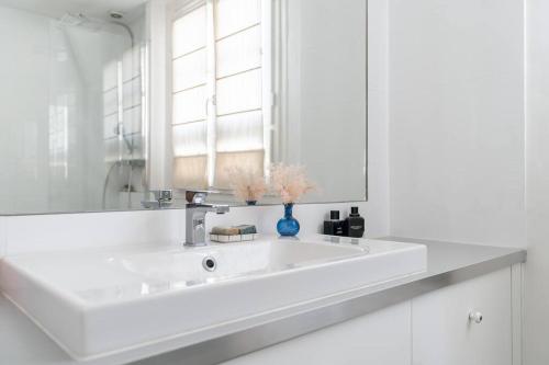 ein weißes Badezimmer mit einem Waschbecken und einem Spiegel in der Unterkunft Charmant appartement in Neuilly-sur-Seine