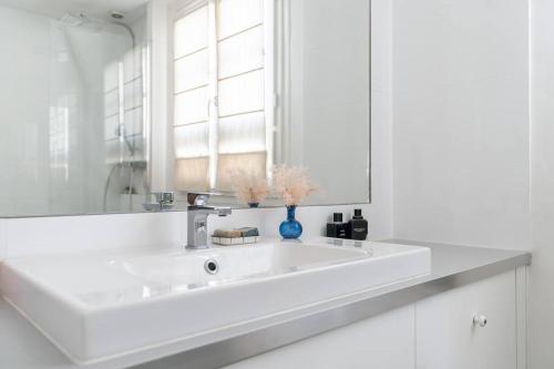une salle de bain blanche avec un lavabo et un miroir dans l'établissement Charmant appartement, à Neuilly-sur-Seine