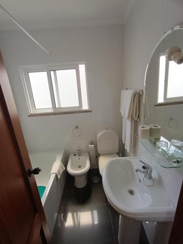 een witte badkamer met een wastafel en een toilet bij Casa 42 in Monção