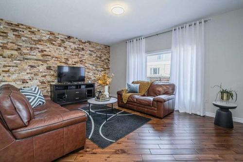 a living room with leather furniture and a brick wall at Cozy Homestay Waterloo Airport II in Kitchener